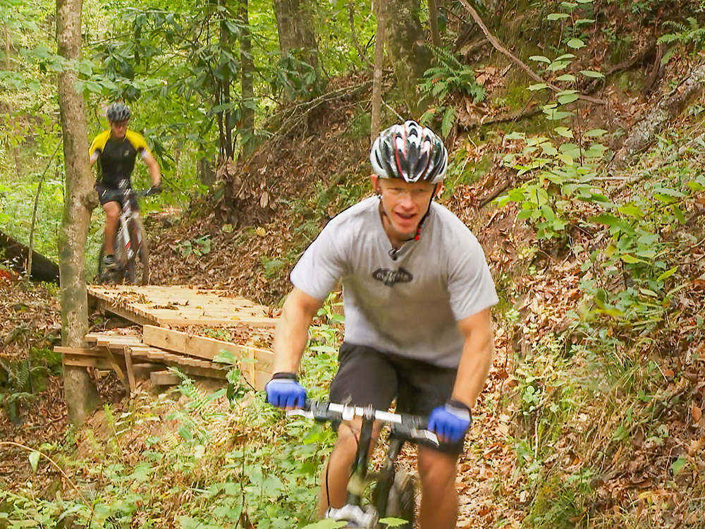 two bicyclists ride the trails cross wooden bridge while biking the beastwhile biking the beast near St.