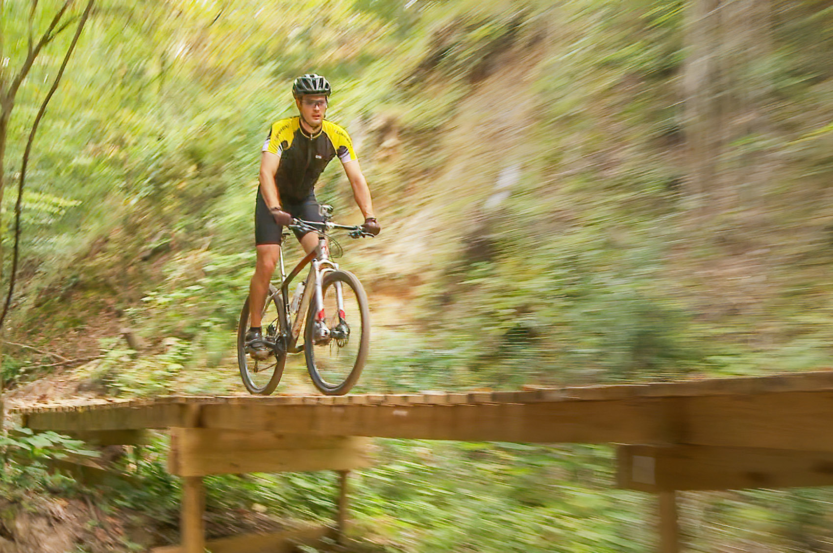 Mountain biker crosses wooden bridge biking the beast trail at St. Francisville Louisiana