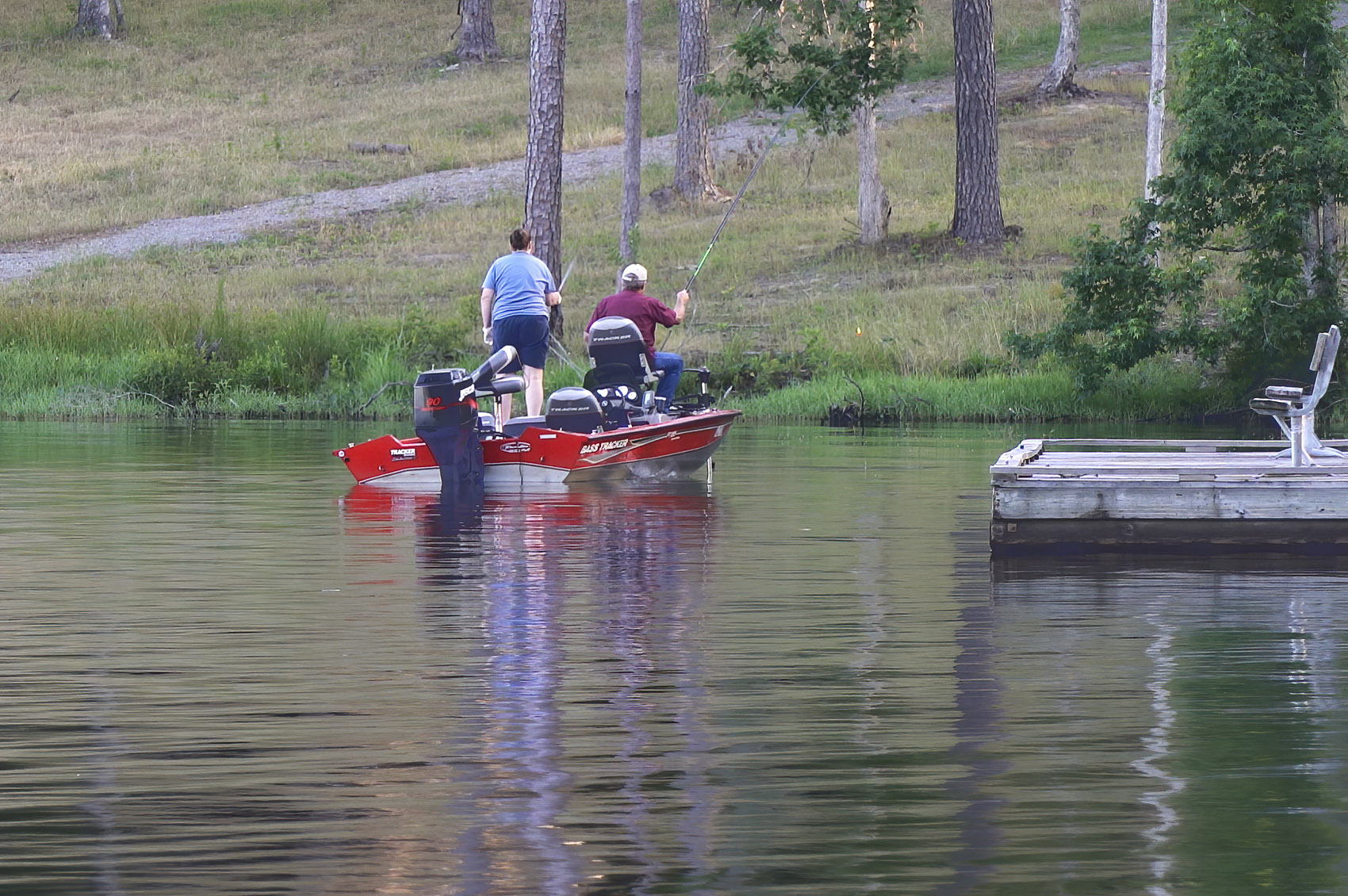 man and woman in bass boat fishing near shoreline and pier in Caney Lake in Jimmie Davis State Park