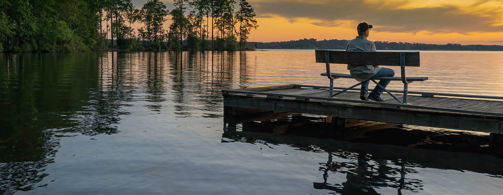 man sitting on dock in peaceful setting on Caney Lake at sunset