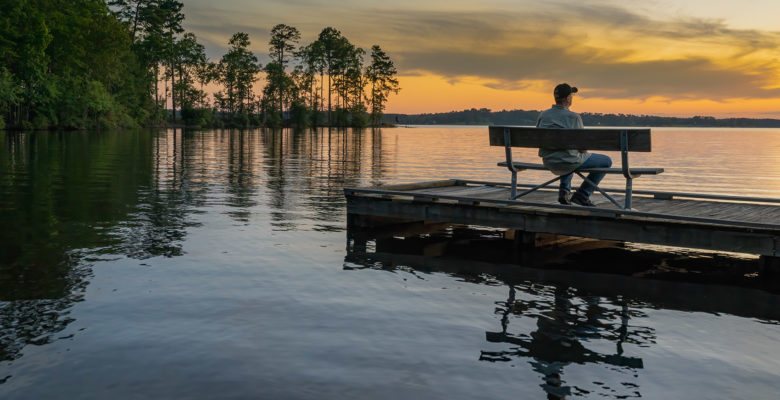 man sitting on dock in peaceful setting on Caney Lake at sunset