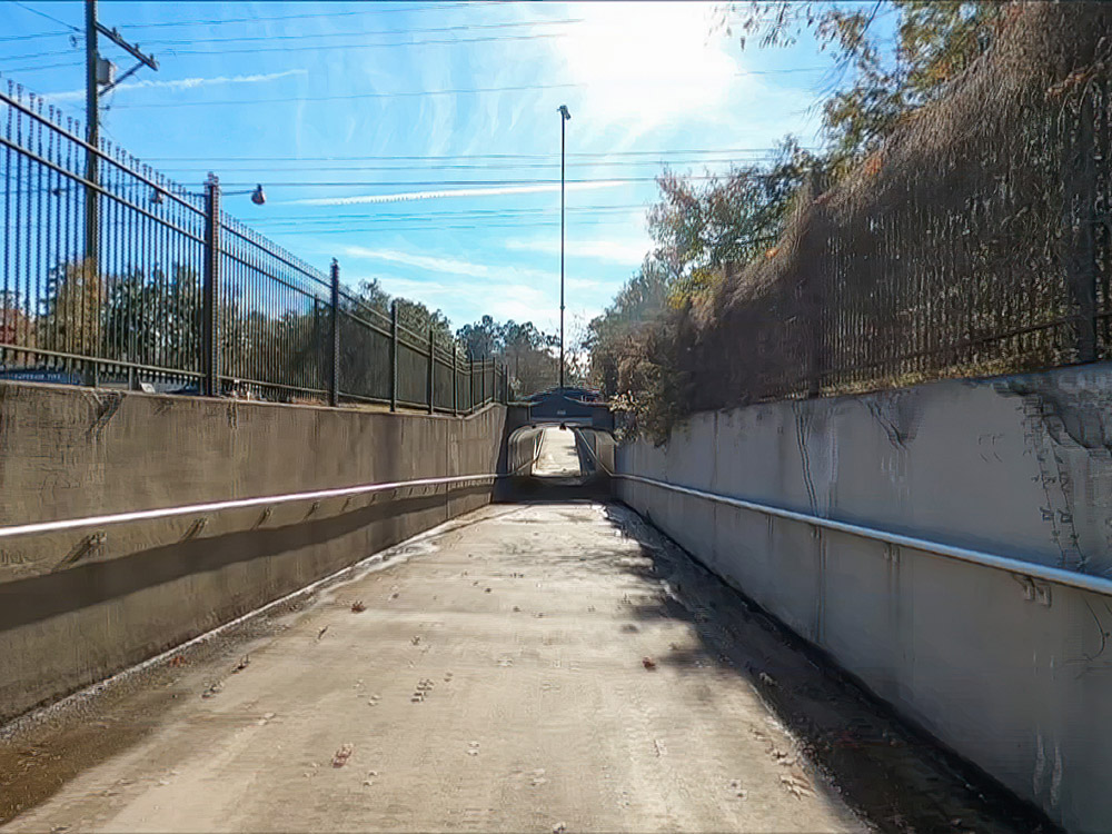 paved bike and walking path tunnel below highway on a bright sunny day