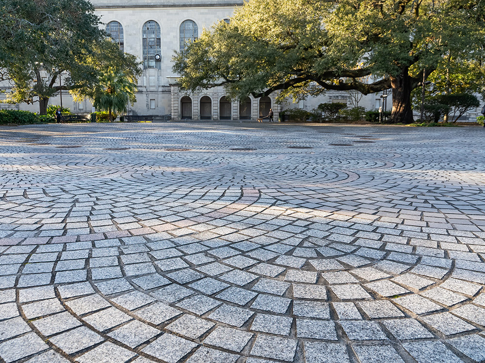 gray tiled plaza and oak trees is a gathering place in historic  Congo Square in New Orleans