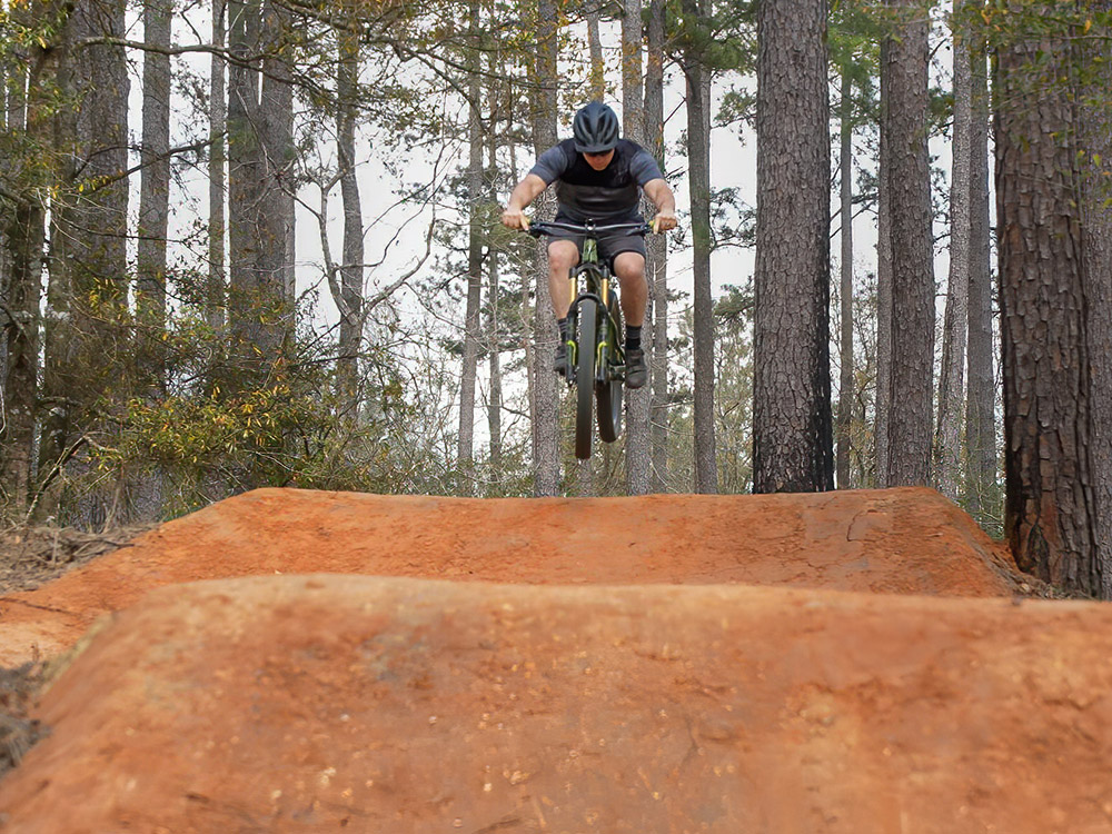 bicycler flies above several jump features on mountain bike trails in Bogue Chitto State Park Louisiana