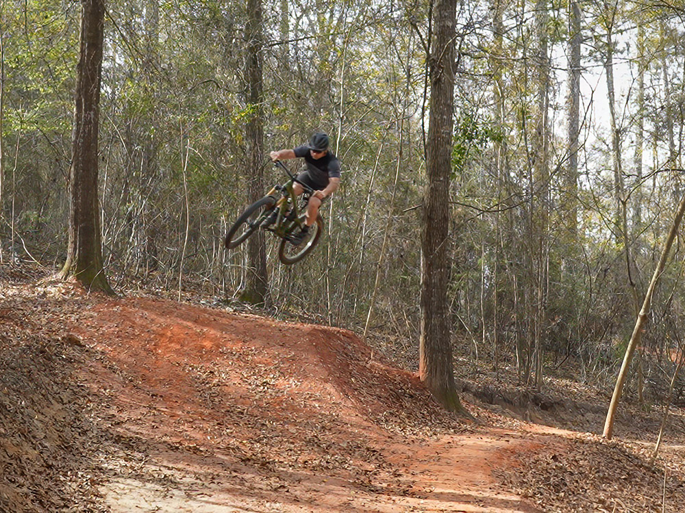 biker flies over dirt hill on mountain bike trails in Louisiana's Bogue Chitto State Park