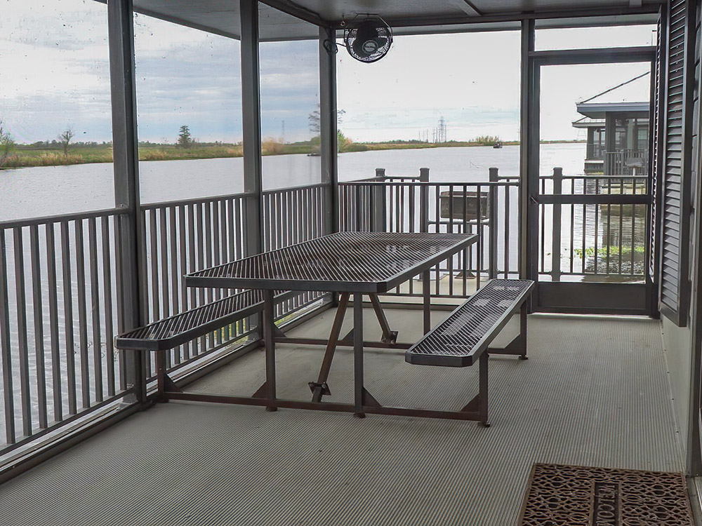 screen porch with picnic table overlook canal and marsh