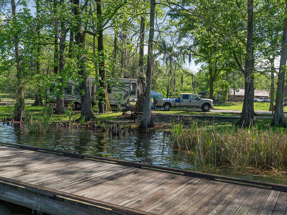 fishing pier and camper on shoreline of Lake Bruin State Park with cypress trees Louisiana