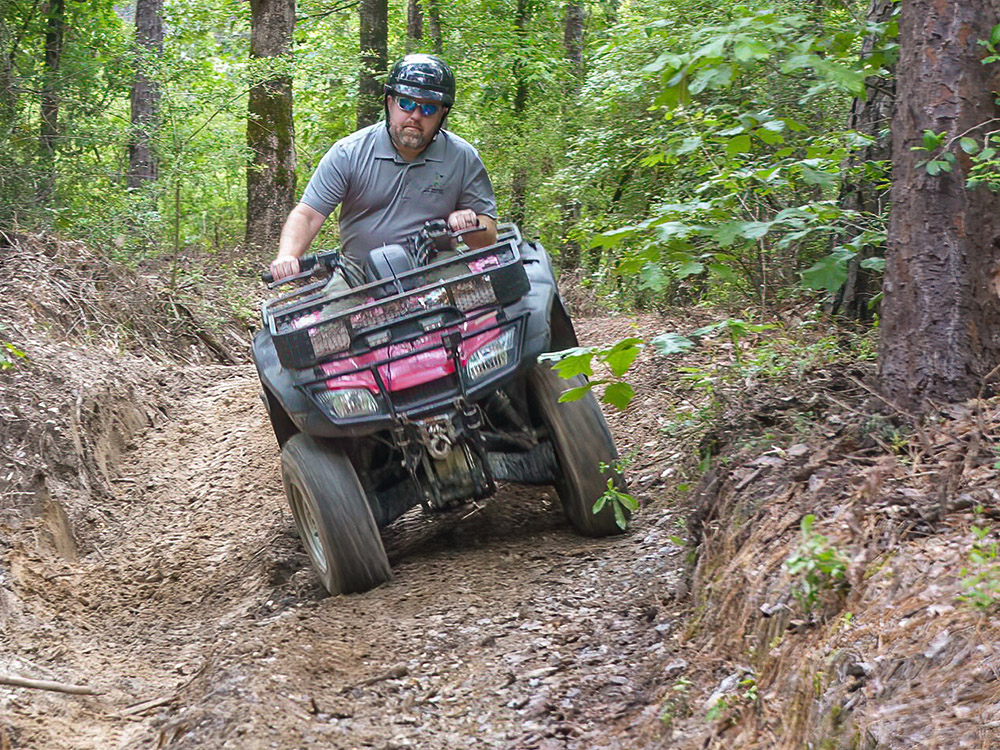 man on atv rides trail through woods