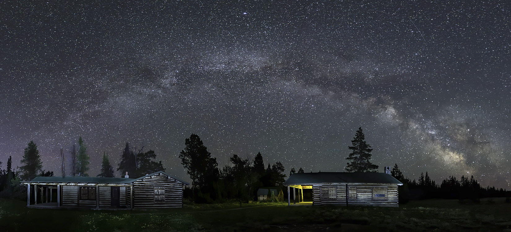 Panoramic view of milky way over homestead in Grand Tetons National Park