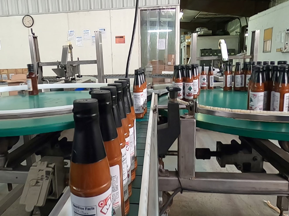 bottles of Louisiana hot sauce move down production line at Panola Pepper