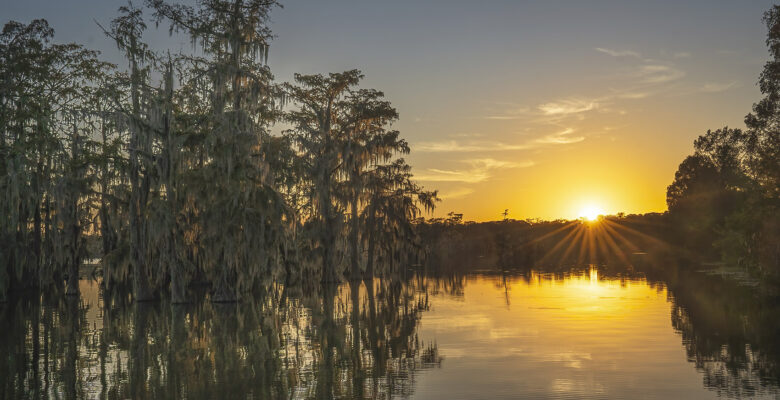 setting sun cypress trees over Louisiana lake