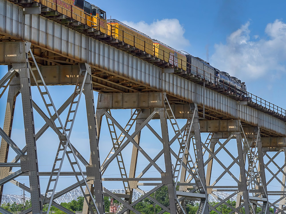 steam locomotive pulls passenger cars up Huey Long Bridge New Orleans