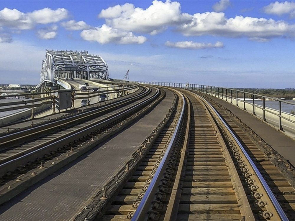 railroad tracks on top of the Huey Long Bridge with steel superstructure in the background
