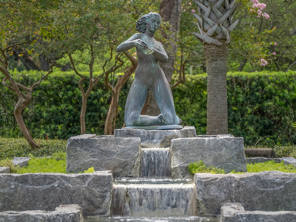 bronze statue of woman above fountain in sculpture garden in New Orleans