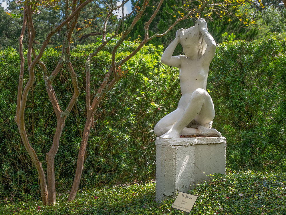 stone statue of woman bather near trees