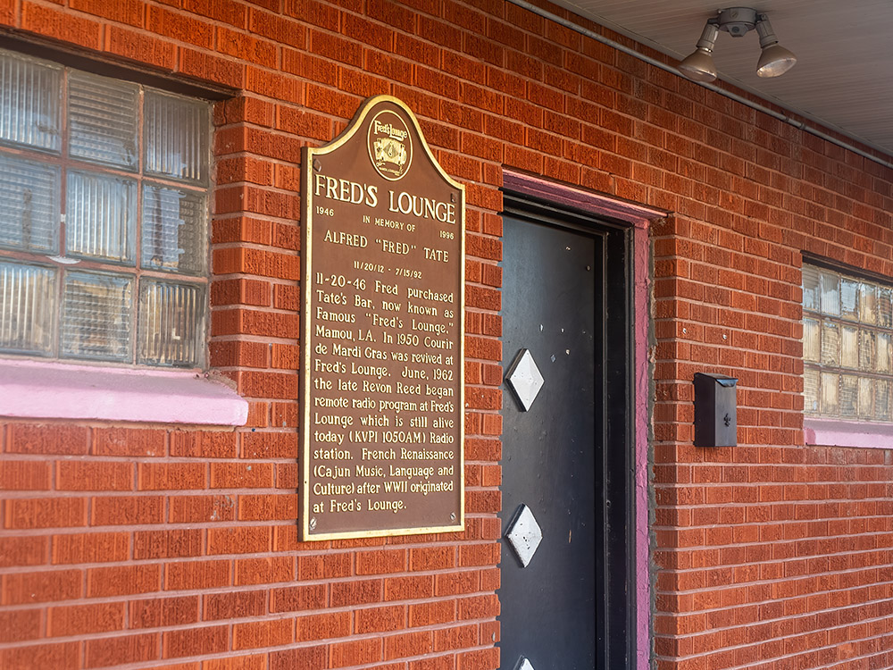 historic marker by the black door entrance to Fred's Lounge in Mamou Louisiana