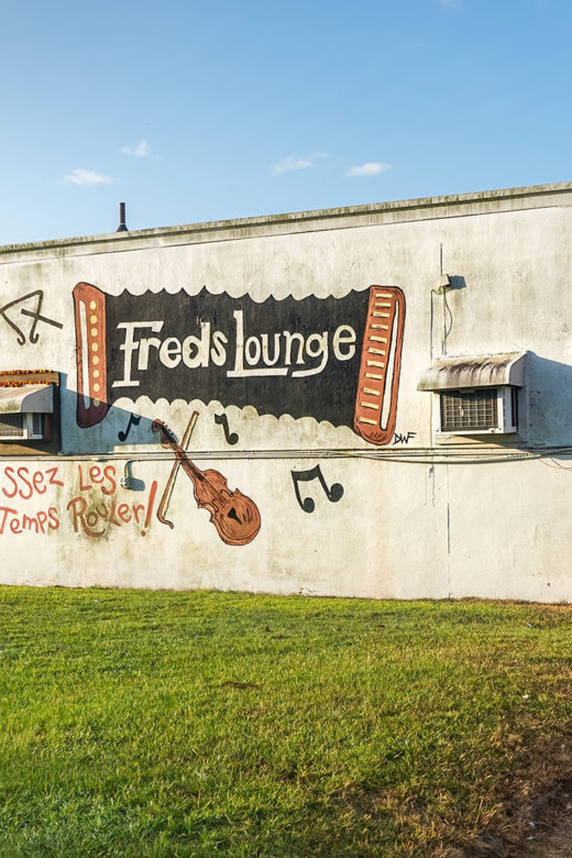 Fred's Lounge painted on side of white building with accordian fiddle and musical notes