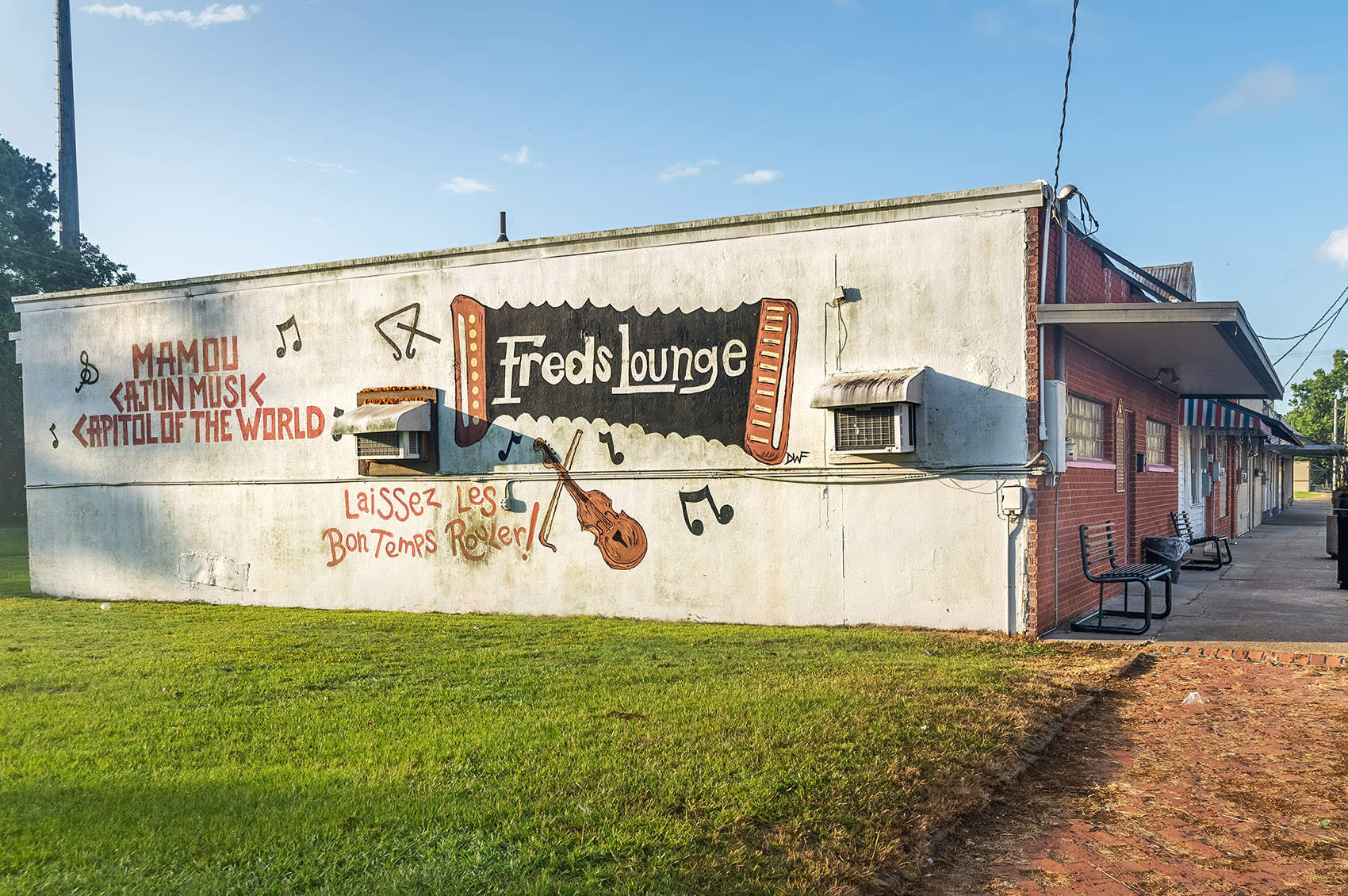 Fred's Lounge painted on side of white building with accordian fiddle and musical notes