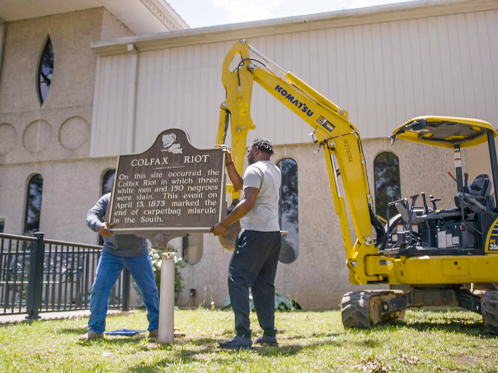 workmen with yellow crane remove historical marker of Colfax Riot