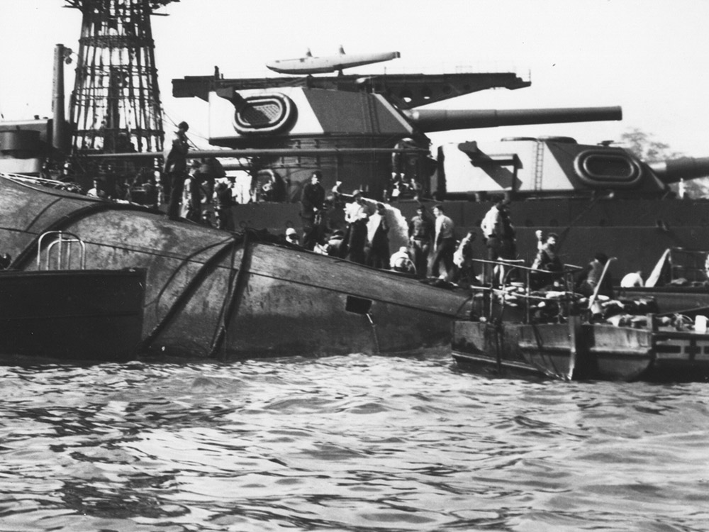 capsized USS Oklahoma at Pearl Harbor, rescuers stand on capsized hull