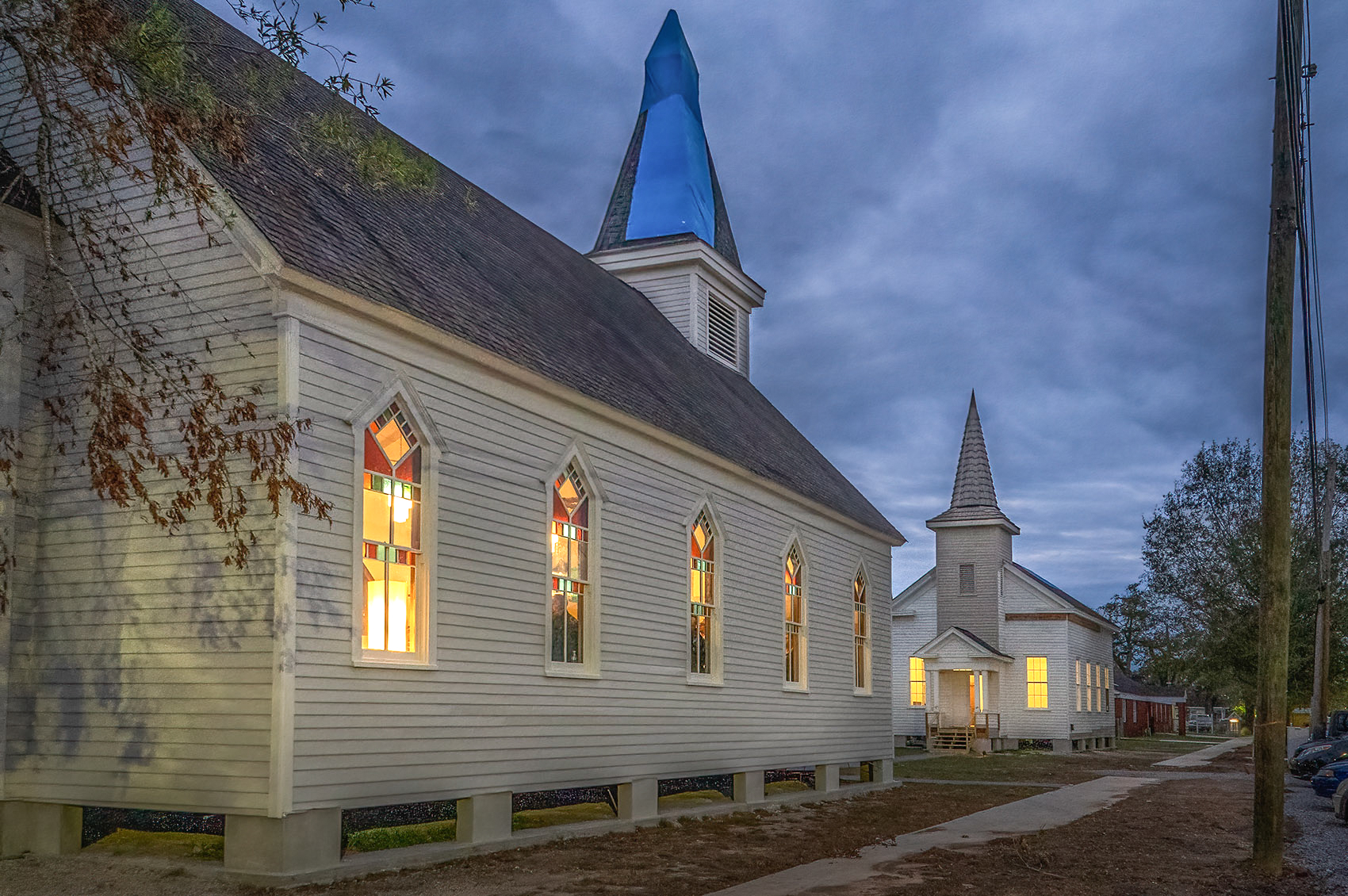 two white churches with steeples facing each other after dark lights on inside