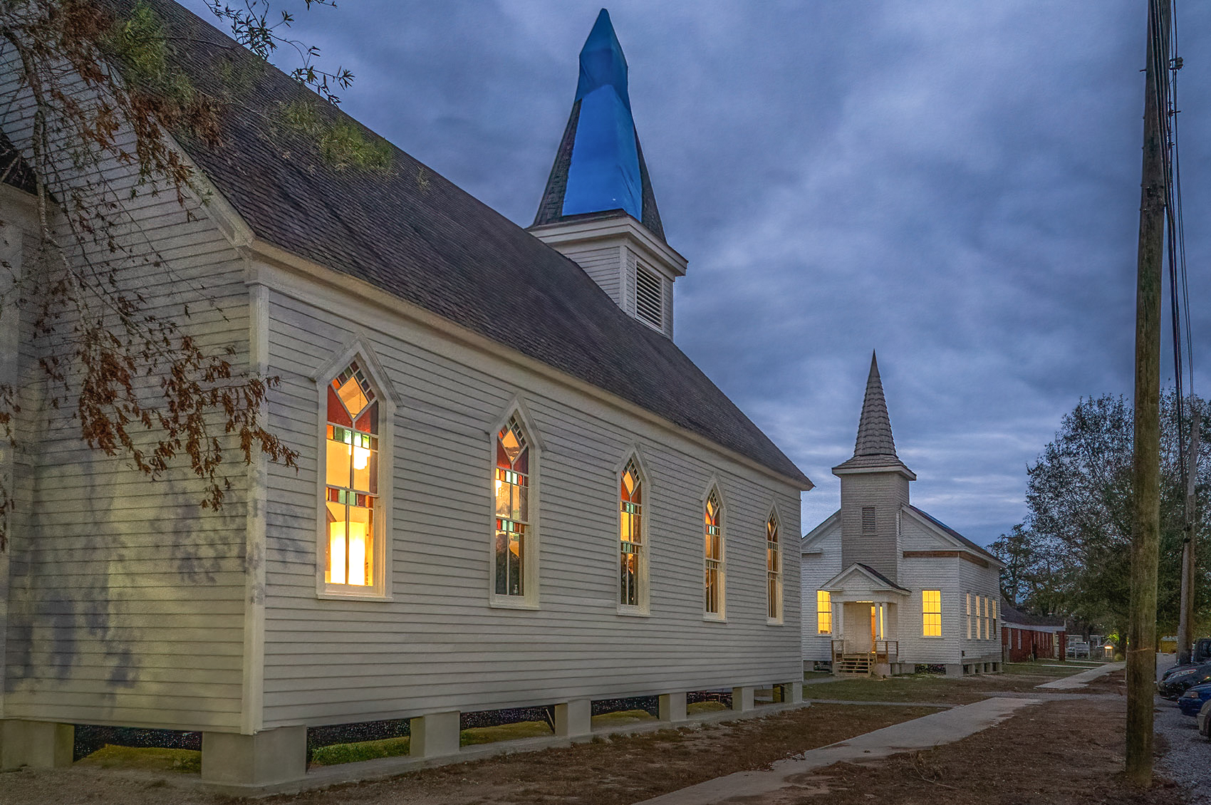 two white churches with steeples facing each other after dark lights on inside