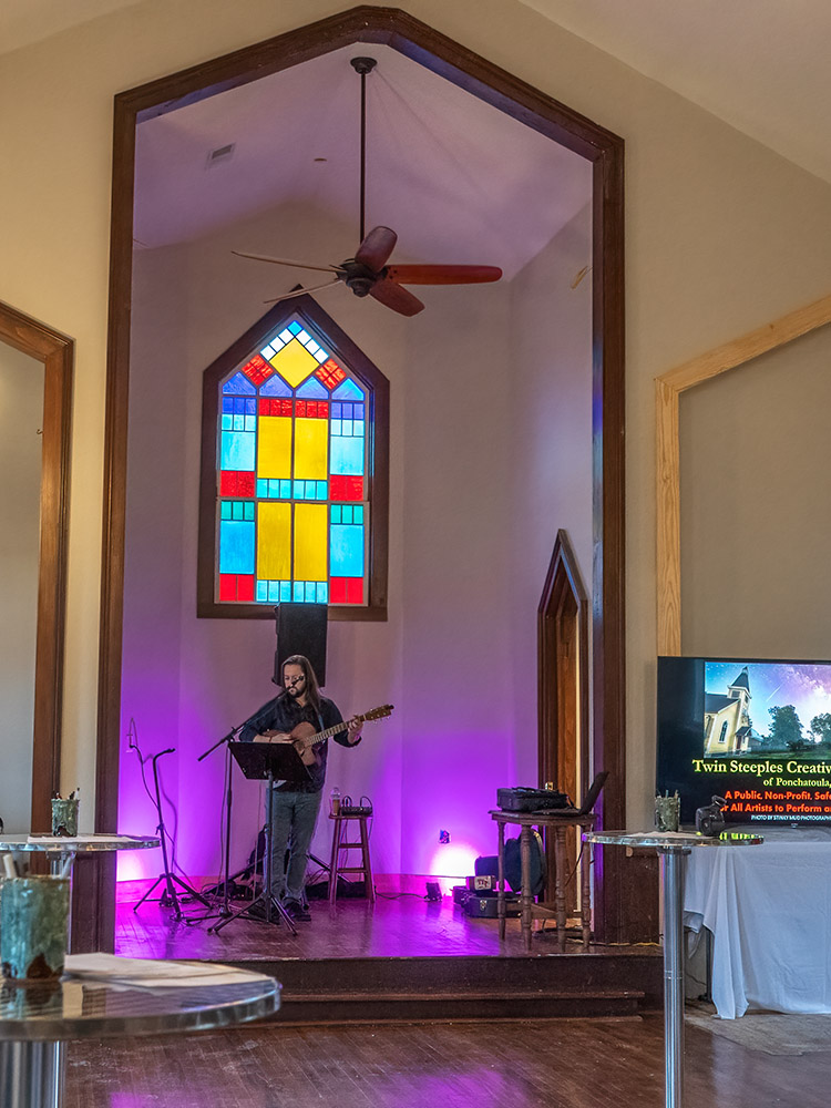 musician performs inside old church with stained glass window