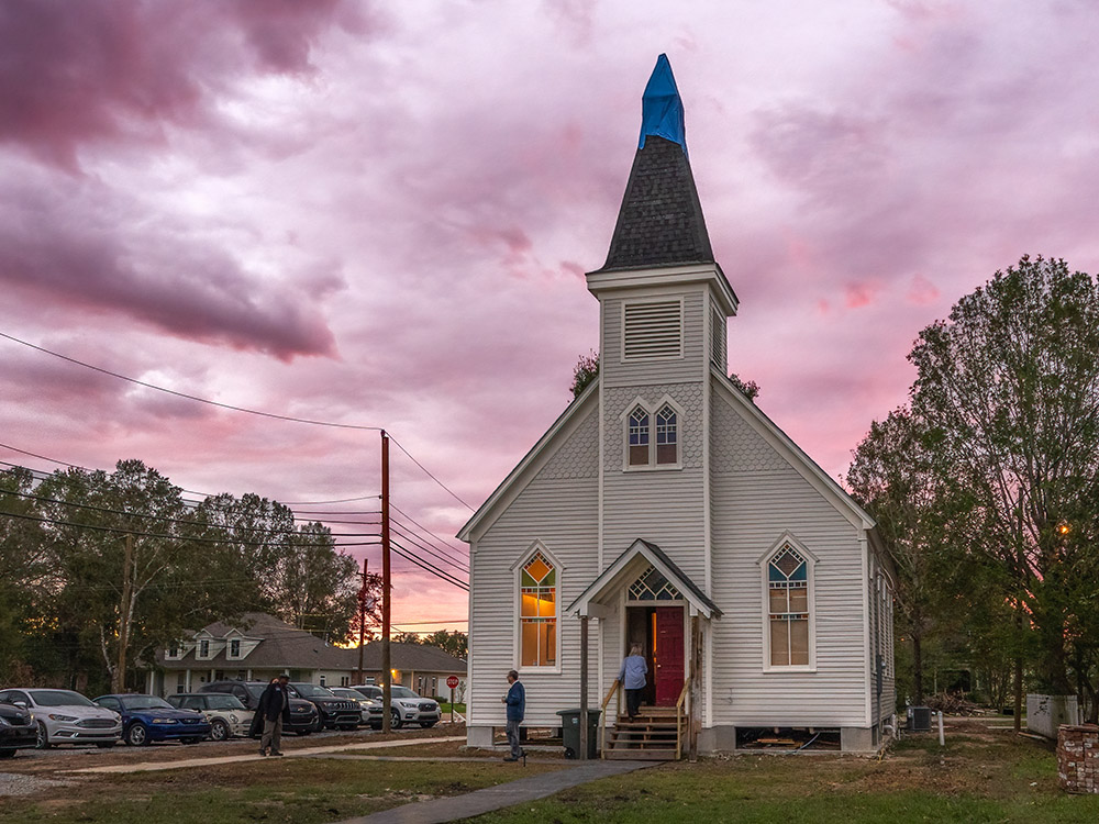 rose colored sunset sky and clouds and wooden church with steeple