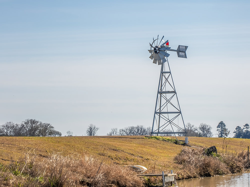 windmill on levee above pond