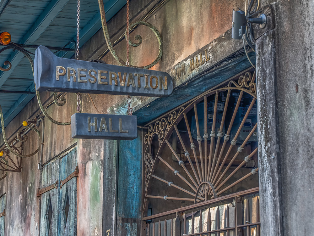 preservation hall sign hands above iron gate entrance to old building