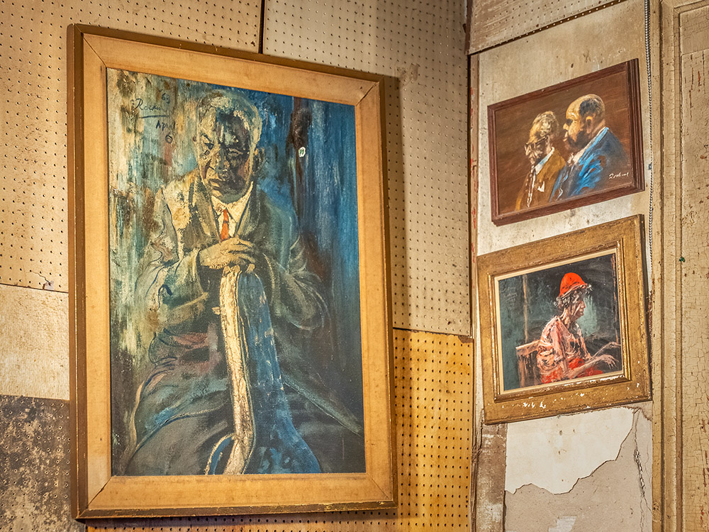 old paintings of jazz musicians hang on unpainted walls of Preservation Hall