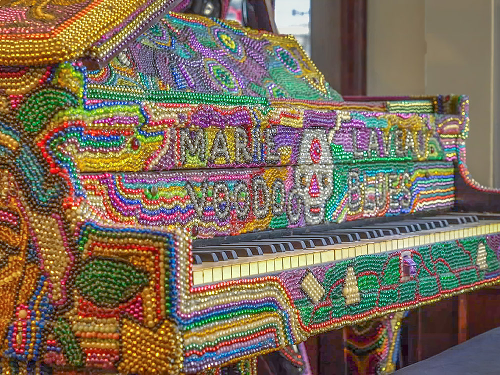 grand piano covered with strands of multi colored beads