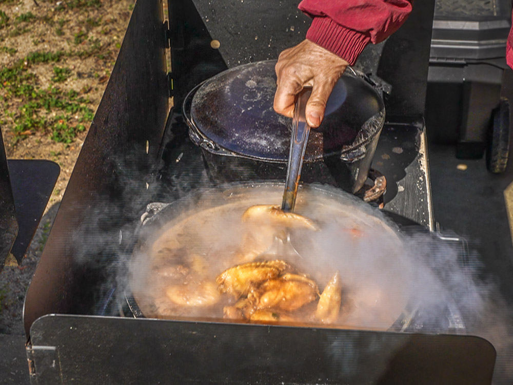 hand stirring a dutch oven pot filled with chicken stew