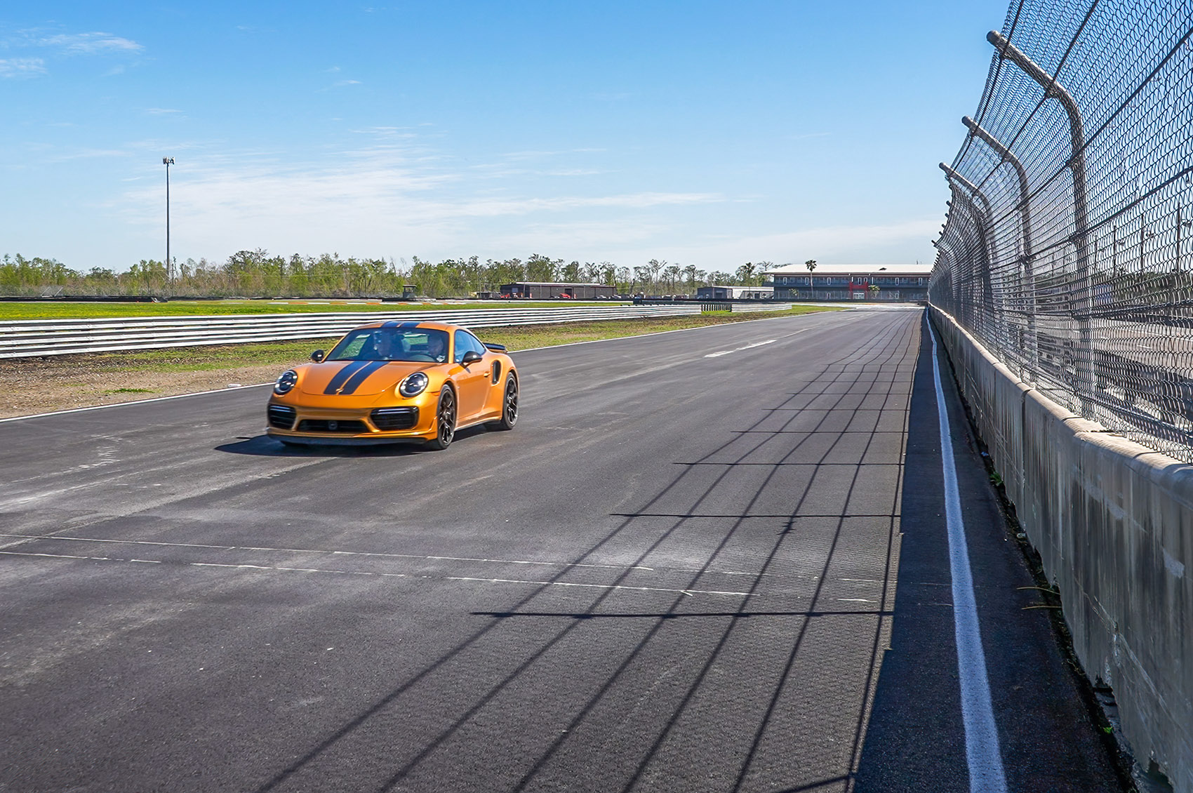 gold Porche car speeding by on track at NOLA Motorsports