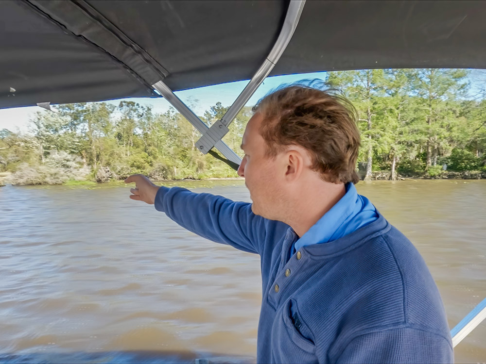 man in blue shirt in boat pointing