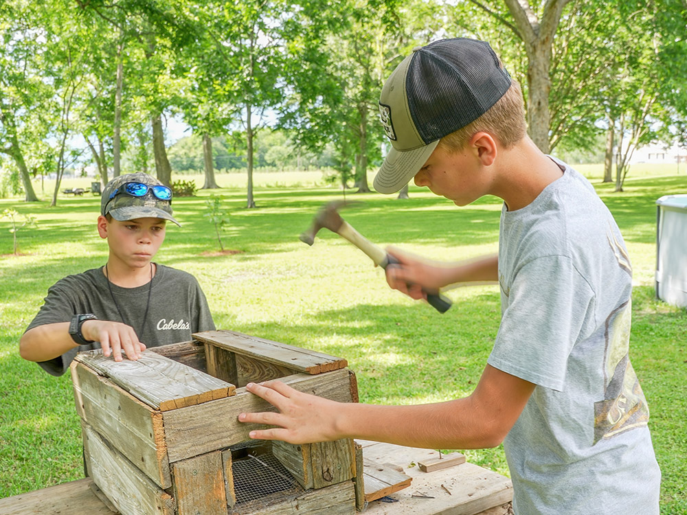 two boys hammering wooden box for trapping Mississippi River shrimp