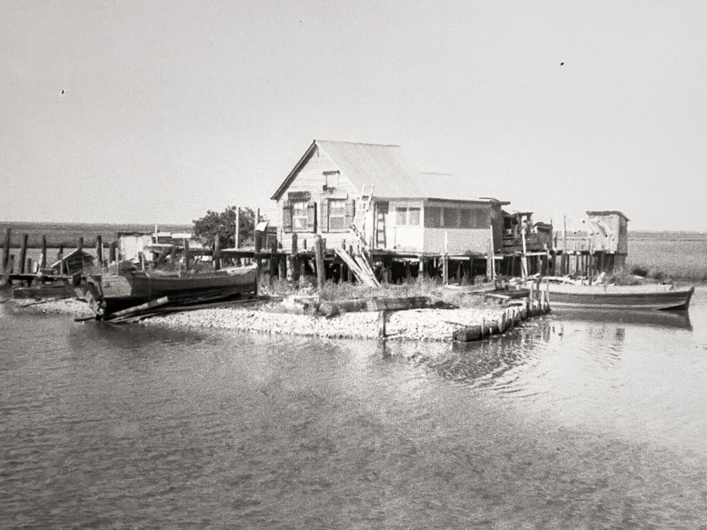 old photograph of home on pilings and fishing boats