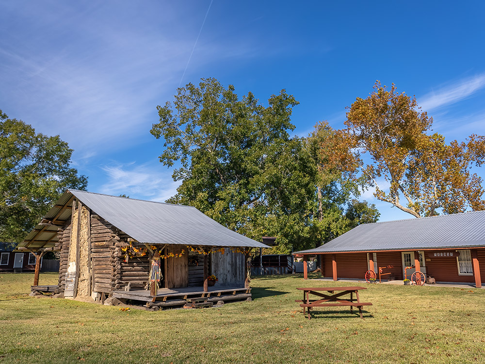 log cabin and museum building with trees and blue sky in Louisiana no man's land
