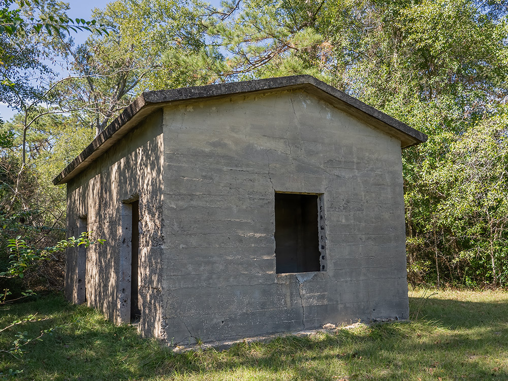 small abandoned concrete jail house near trees