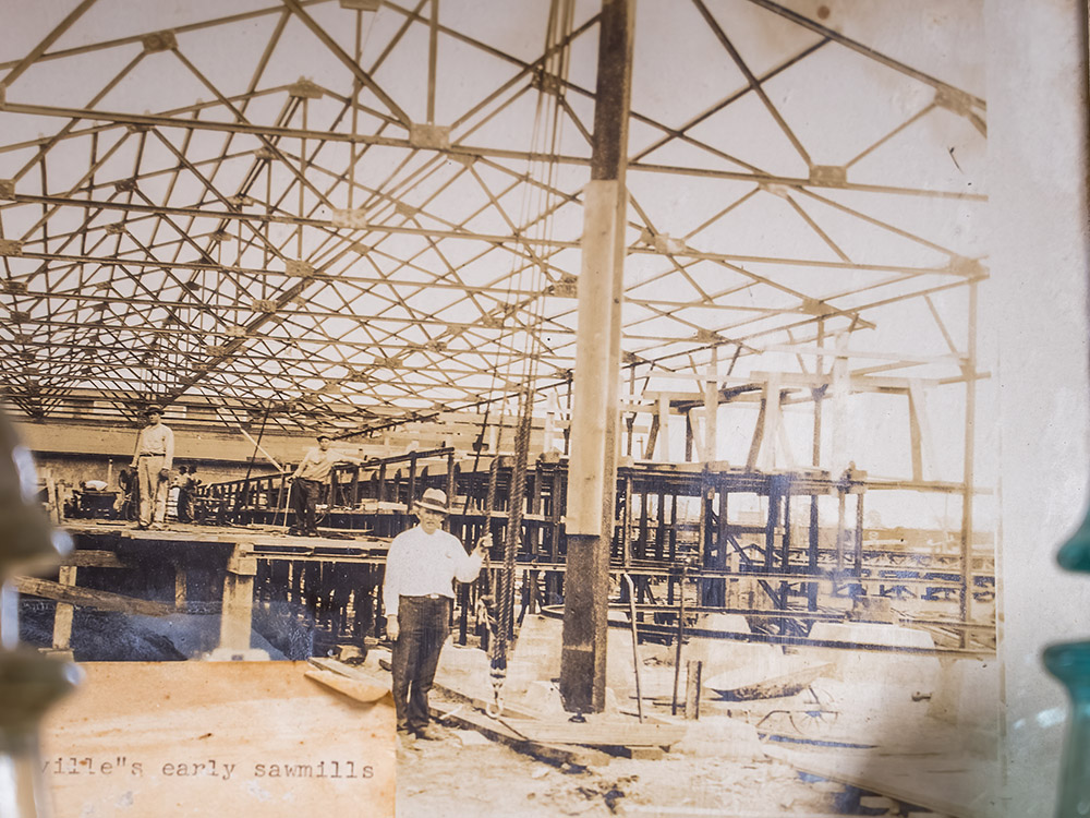 man in hat standing under framed building sawmill