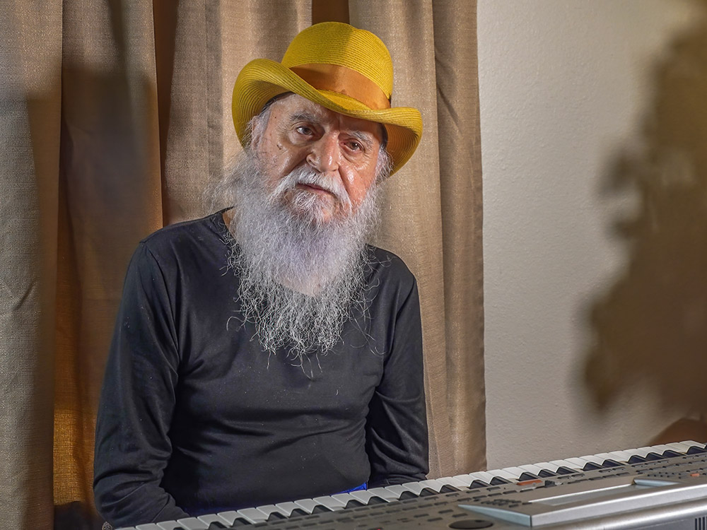Tommy McLain man with gold hat and white beard and hair seated at piano