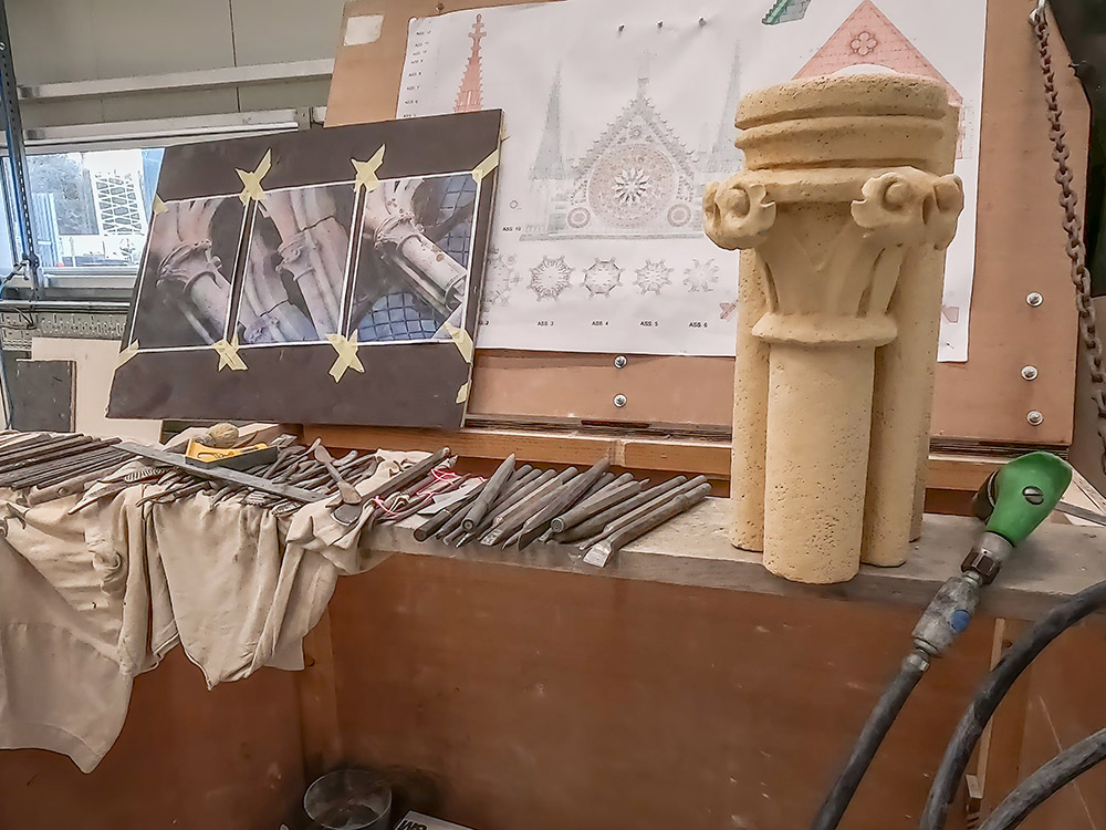ornamental stone work and tools on table with photographs of architectural features in Notre Dame