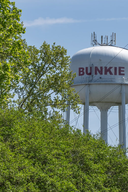white bunkie louisiana water tower and trees with blue sky