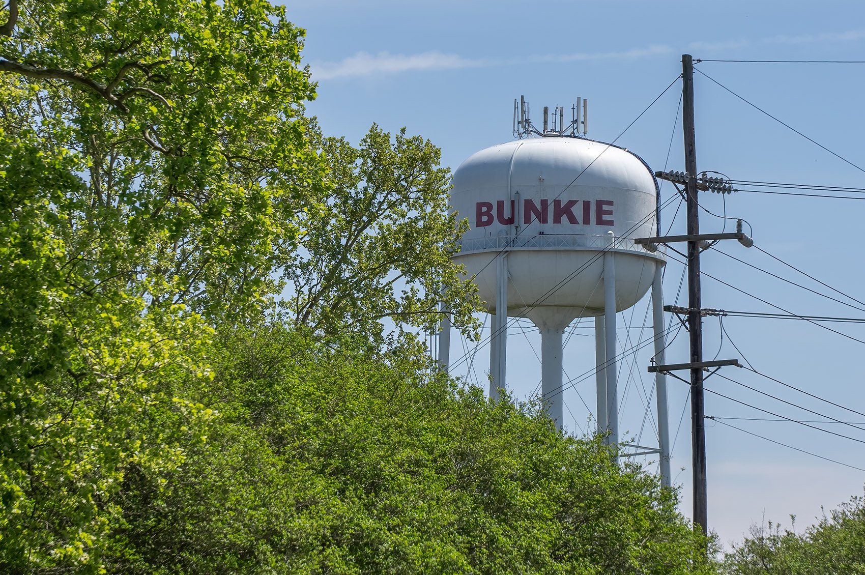 white bunkie louisiana water tower and trees with blue sky