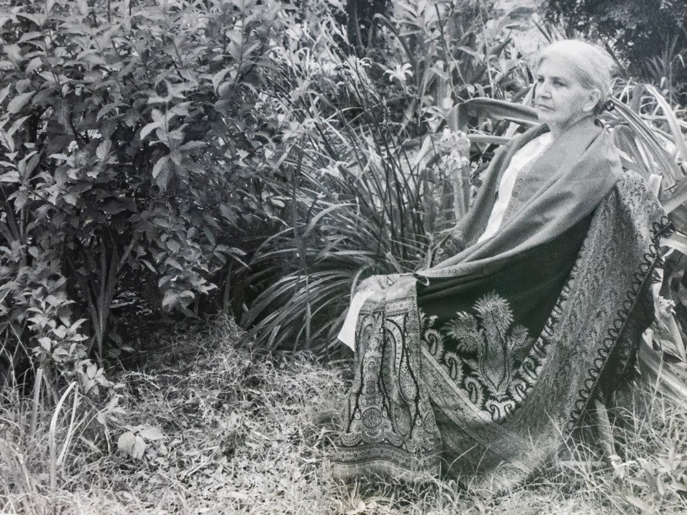 old black and white photograph of women wrapped in blanket sitting in garden