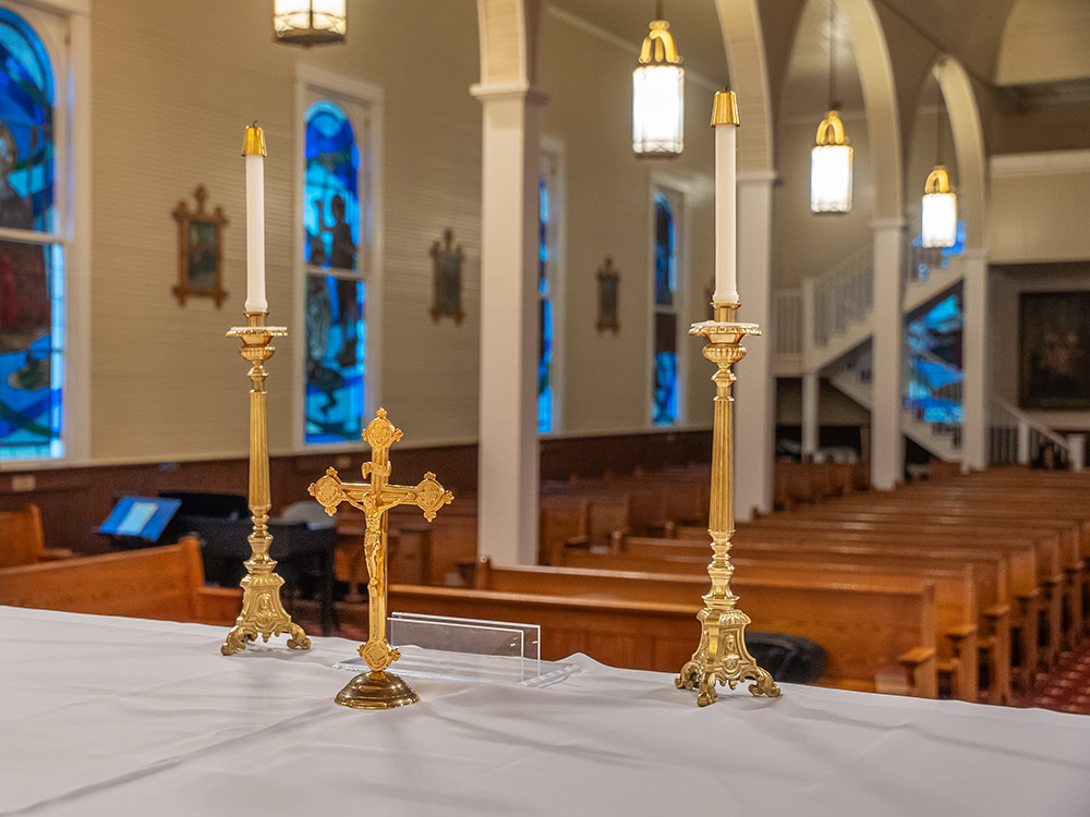 gold colored brass cross and candle holders on altar inside church