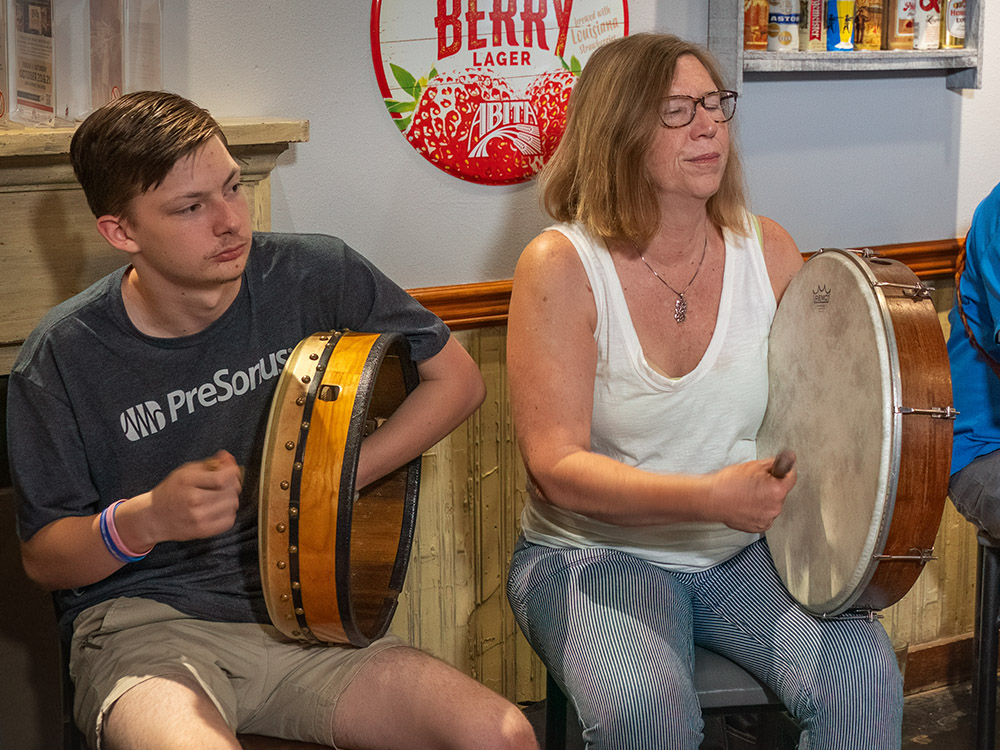 man and woman sitting side by side play bodhran