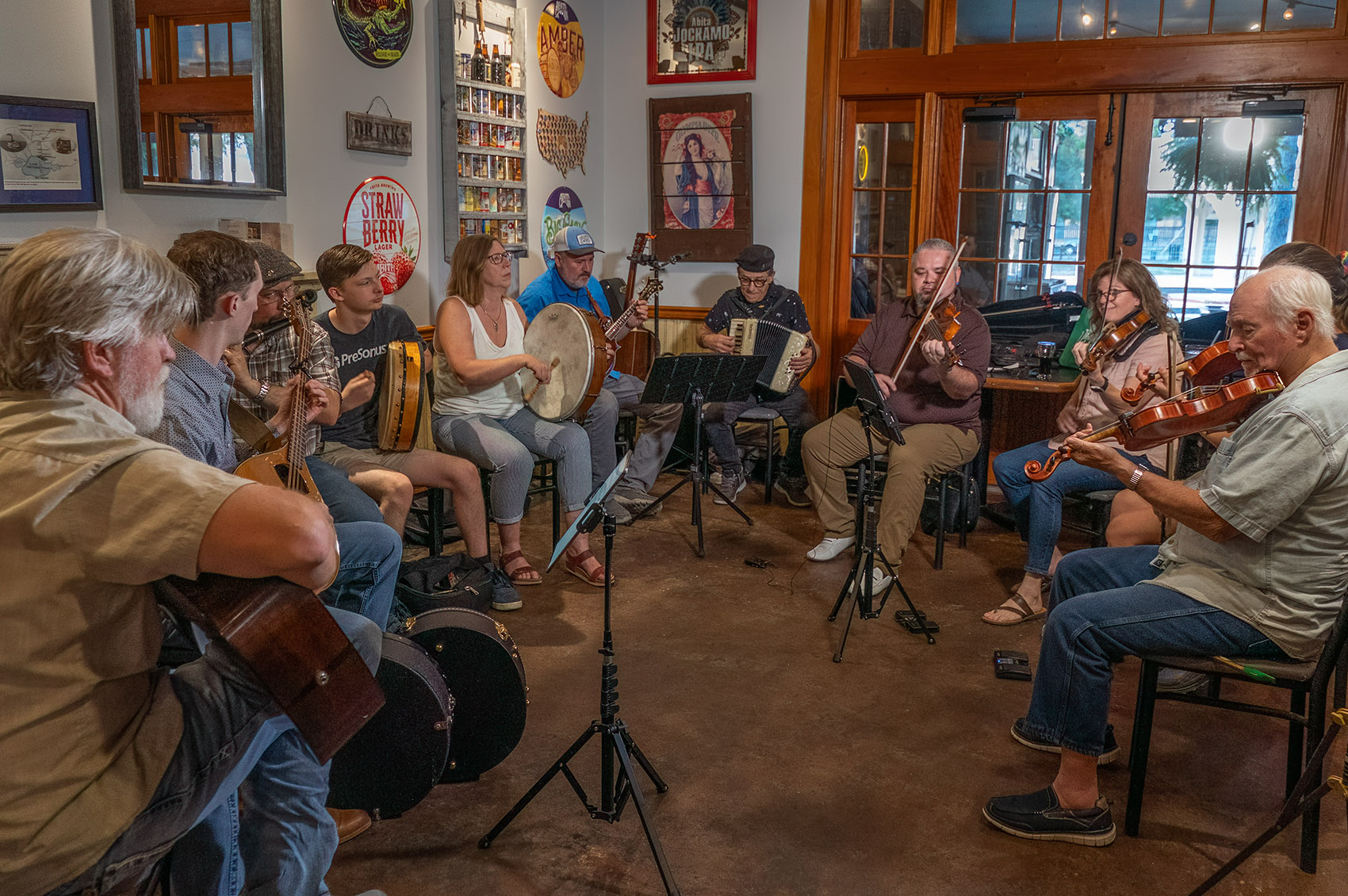 musicians playing acoustic instruments sit in semi-circle to play Louisiana Irish music