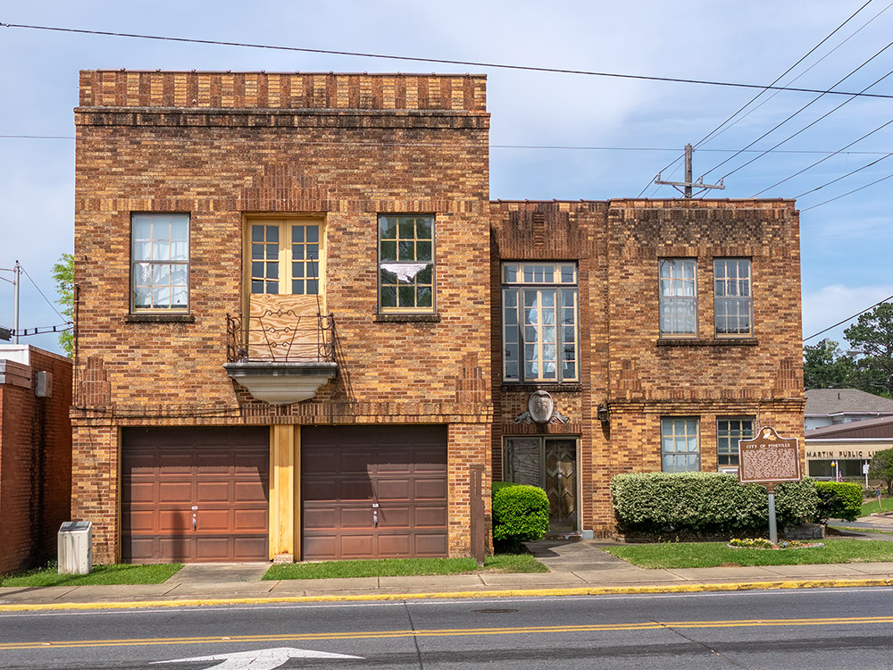 orange and brown brick 2-story building with double garage and windows.