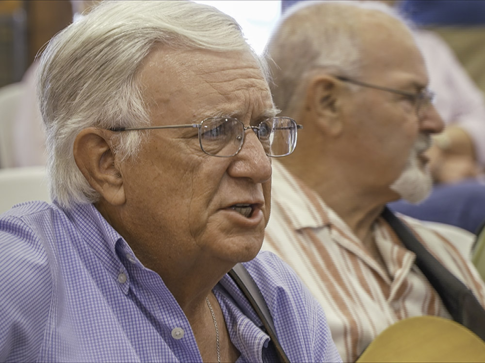 man with gray hair and classes wearing blue shirt singing cajun music